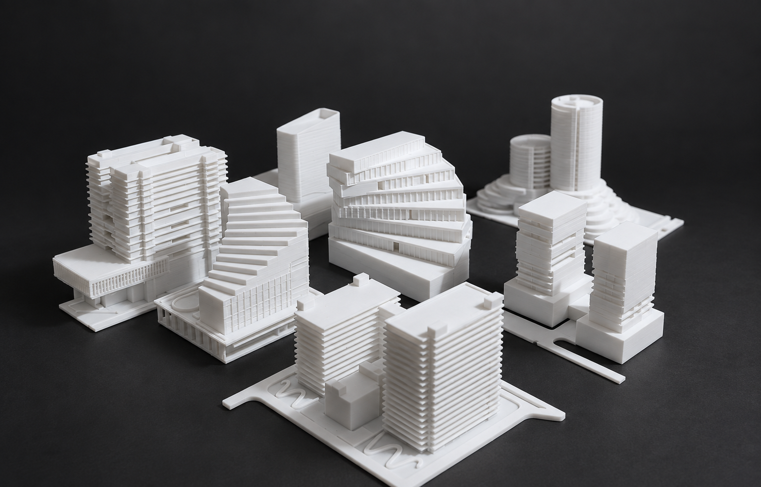 Collection of white architectural models with stepped and curved towers
