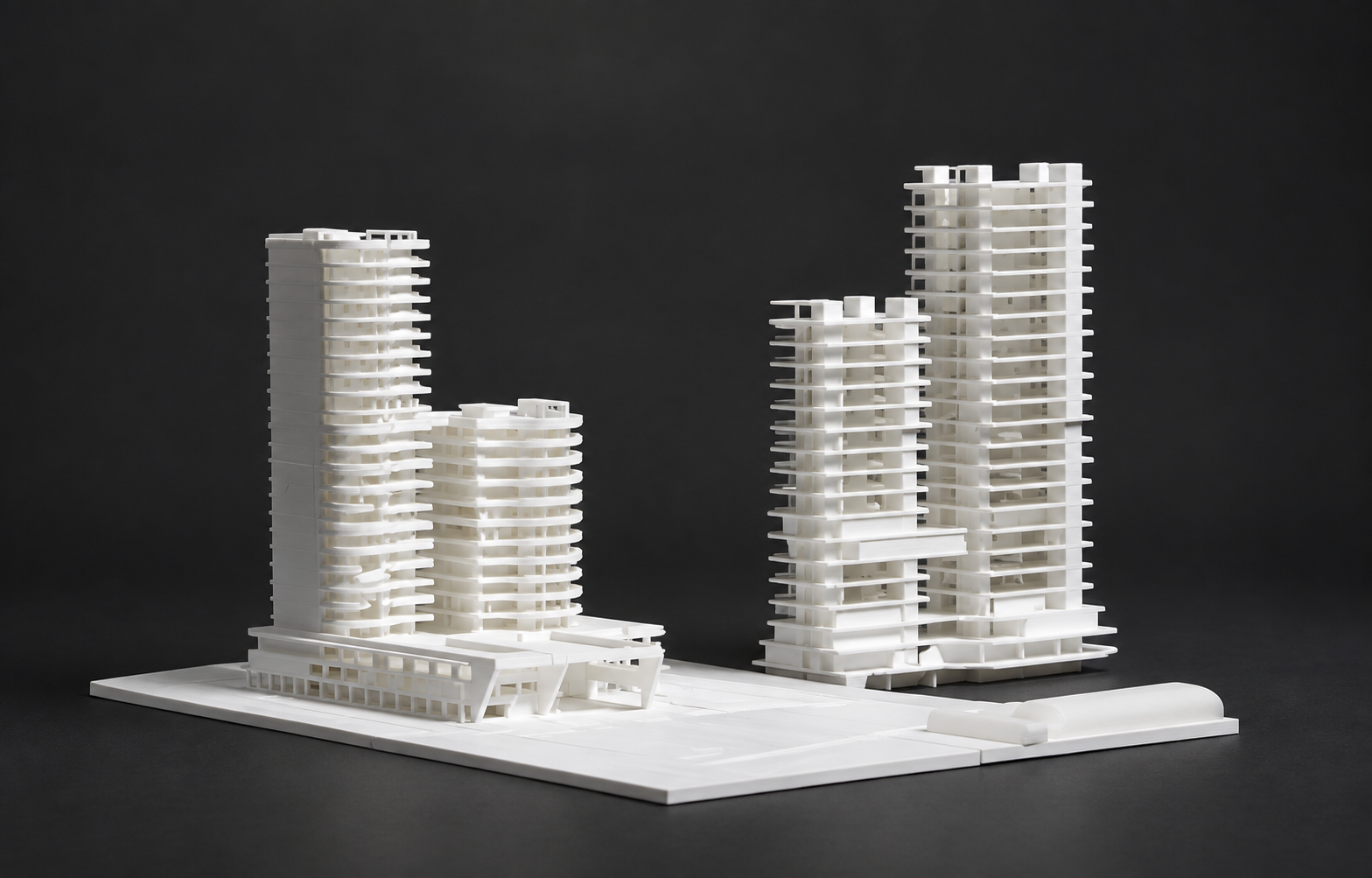 Two white paired-tower architectural models on a dark studio surface