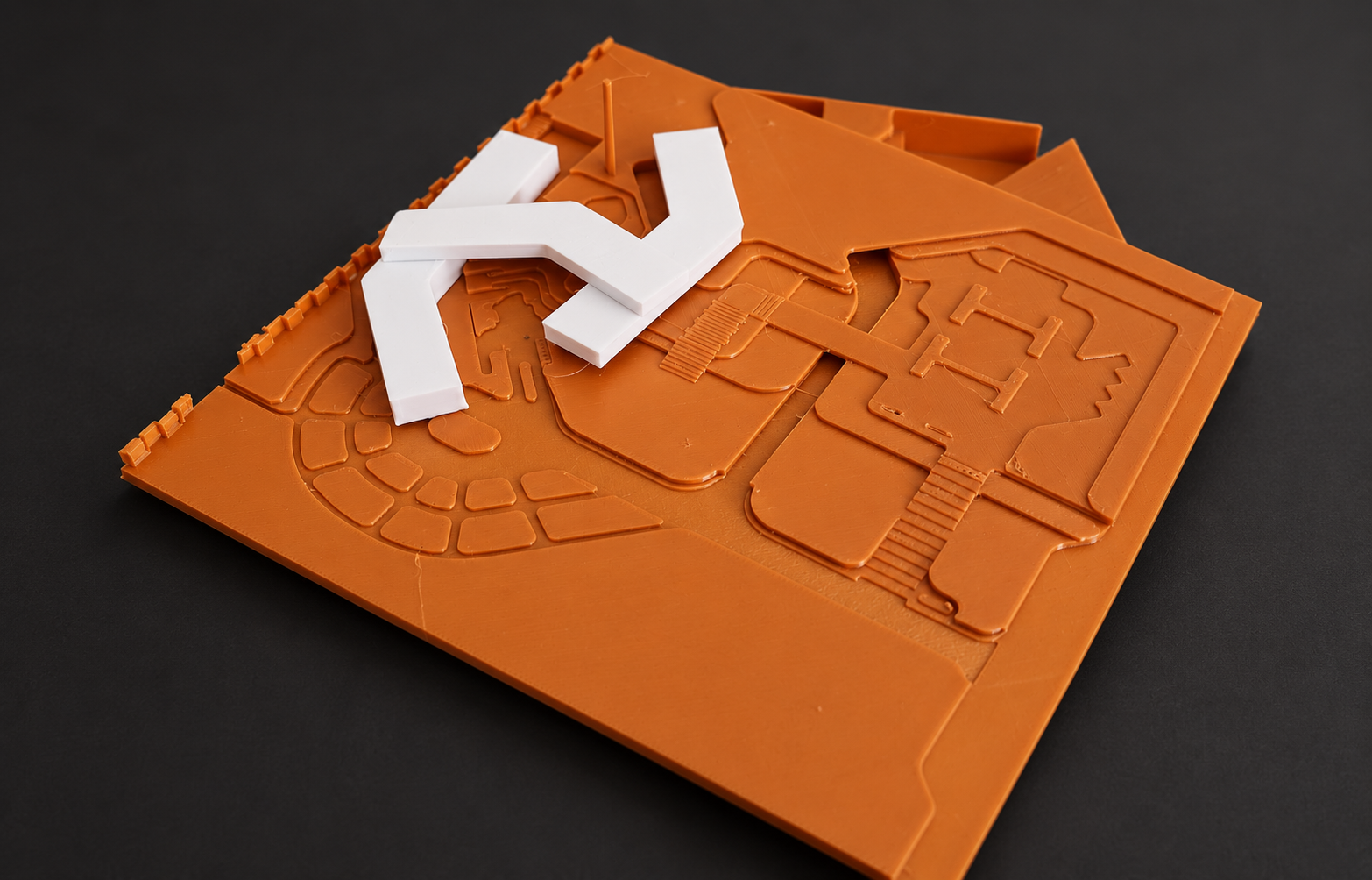 Orange terrain model with white angular building forms and detailed paths