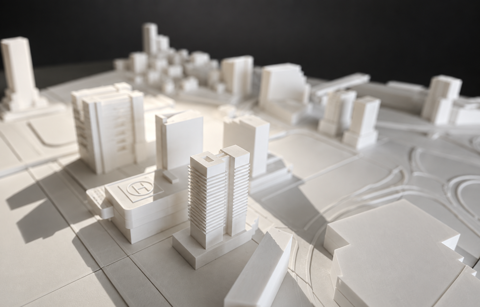 Close-up of white twin towers and a rooftop helipad in the site model